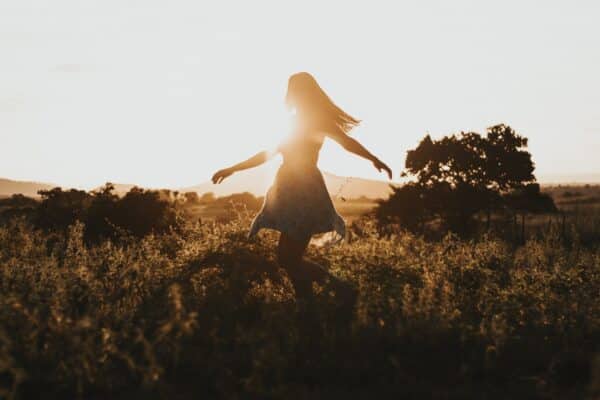 A Woman is dancing happily in the sunset.